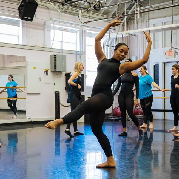 A dance major student performs in front of the class in a dance studio.